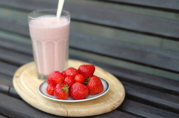 Strawberry on a plate and cocktail on the background