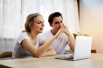 Happy couple lover talking and waving hand in a video conference on line with a laptop for contact frindship at home.