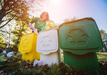 Volunteer girl sorts garbage in the street of the park. Concept of recycling. 