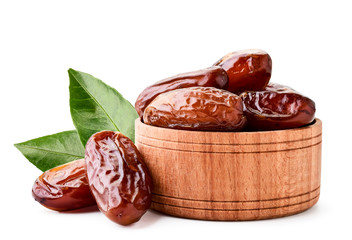 Dates fruit in a wooden plate with green leaves on a white. Isolated
