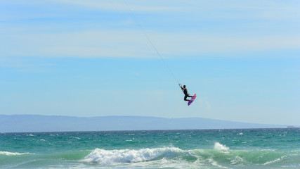 kite surfer flying while sailing in a paradise spot to practice the sport