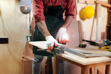 In selective focus of Hands with glove get a plane and shave off timber board,wood work,Lens flare effect,blurry light around