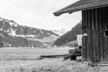  old wooden barn stands in the valley with the Alps in the background