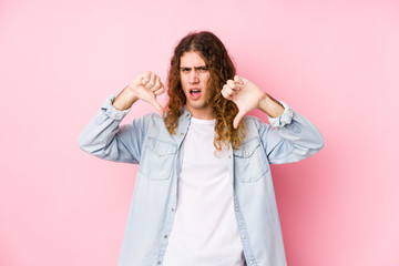 Long hair man posing isolated showing thumb down and expressing dislike.