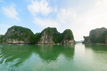 Fototapeta na wymiar Ha Long Bay, unique limestone rock islands and karst formation peaks in the sea, famous tourism destination in Vietnam. Clear blue sky.