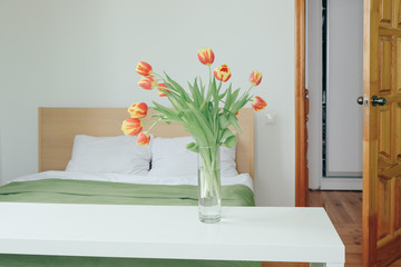 Bouquet of red yellow tulips in a bedroom on the background of the bed.