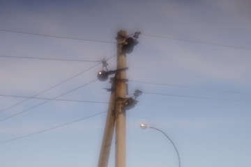  Old stone pillar with wires on the blue sky background. Soft dreamy image