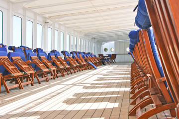 Wooden teak deck chairs and sun loungers with blue  pillows and upholstery on deck of luxury...