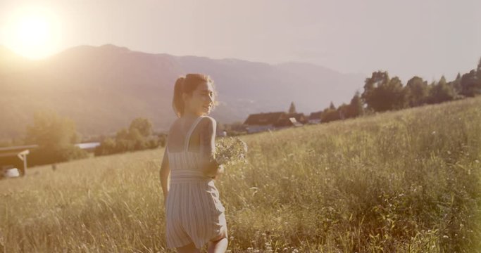 Girl runs across the field. In the hands of a bouquet of wildflowers. Low sunset. The concept of freedom, unity with nature. Shot on movie cameras with 12 bit colors.