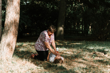 Old woman doing cpr to a fallen girl due to heart attack