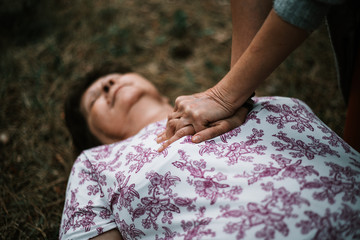 Fainted old woman having a heart stroke outdoors and receiving cpr