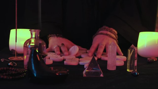 Medium shot of witchy hands mixes the runes before the fortune spelling