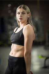 Fototapeta na wymiar Portrait of a girl in a fitness hall in the sports form with a blurred background.