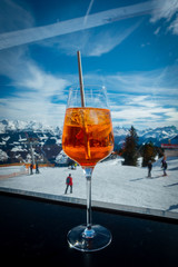 a glass with an orange long drink and in the background are the snow covered mountains