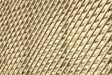 Wall of wooden planks. Lattice from a natural tree for weaving plants. Design for the decoration of buildings. Wood panel fence.