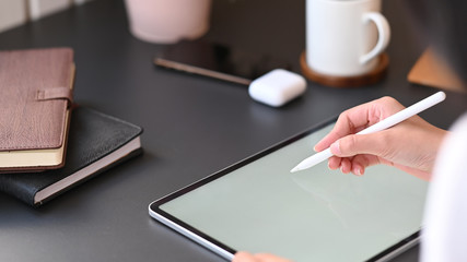 Cropped image of secretary woman's hand holding stylus pen wile writing on computer tablet.