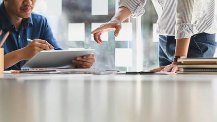 A businessman writing on computer tablet while meeting with colleague.