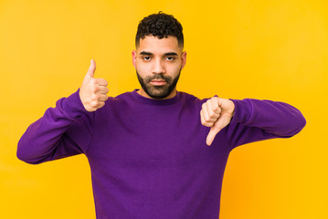 Young mixed race arabic man isolated showing thumbs up and thumbs down, difficult choose concept