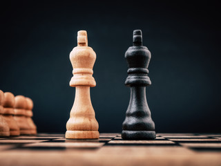Two kings on a chess board standing next to each other representing a rivalry concept between two...