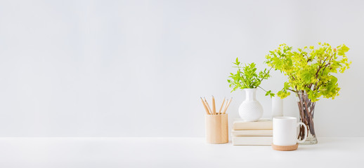 Home office, interior for bloggers workplace with branches with green leaves in a vases, office supplies