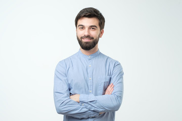 Hispanic young man standing with his arm crossed over white background