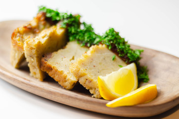 Cut potato cake served with sauce and parsley on a wooden plate