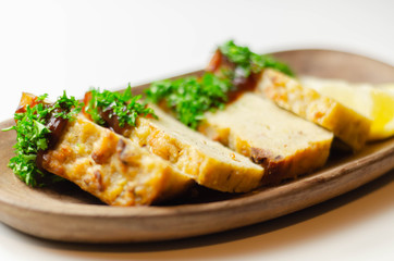 Cut potato cake served with sauce and parsley on a wooden plate