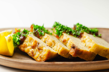 Cut potato cake served with sauce and parsley on a wooden plate