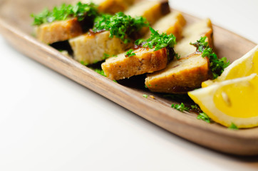 Cut potato cake served with sauce and parsley on a wooden plate