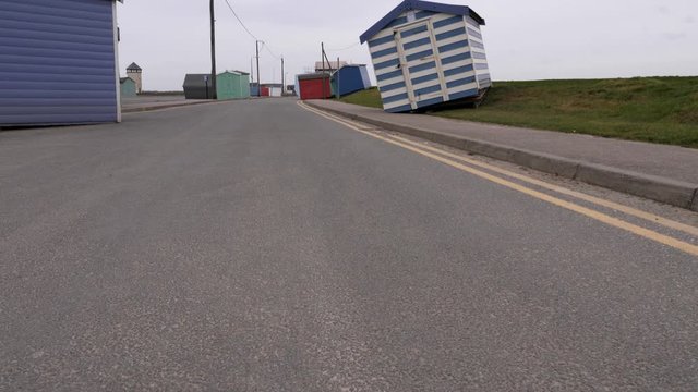 Beach huts that have been moved and dumped on to the road. Damage caused by storm surge created by storm Ciara. Tilt shot.