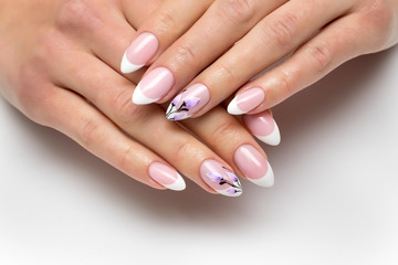 French manicure with painted flowers on sharp long nails closeup on a white background.