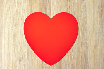 Red heart on natural bleached oak wooden background close up view. Copy space.