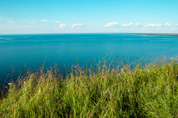 Beautiful landscape scenery cliff meadow, water and blue sky. Cape Andoma, Karelia, Russia