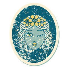 distressed sticker tattoo style icon of a maiden with crown of flowers winking