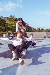 3 Young girls teenage schoolgirls ride skateboard summer park. Casual wear sweater jeans. Emotions happiness, fun, relaxation, smile laughter, best girlfriends, rest after college © byswat
