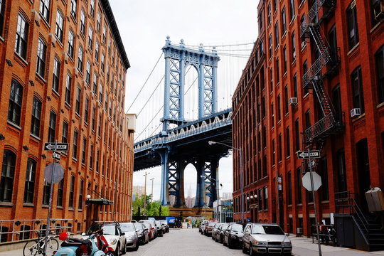 Manhattan Bridge Seen From A Red Brick Buildings In Brooklyn Street In Perspective, New York, USA. Beautiful Classic Apartments In New York City. Beautiful American Street. Famous View.