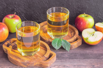 Apple juice in glasses and apples on a wooden table close-up. background with glasses of clear apple juice and fresh red apples.