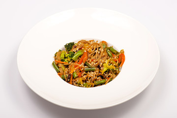 Buckwheat noodles with broccoli, green beans, sweet peppers, Asian-style sesame mushrooms. Vegetarian dish. in a white plate on a white background