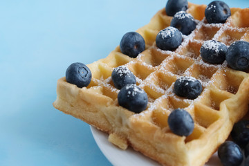 Homemade waffles with fresh blueberries. Viennese waffles. Close-up. Blue background. Delicious dessert or breakfast. Copy space