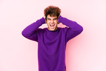 Fototapeta na wymiar Young caucasian man against a pink background isolated covering ears with hands trying not to hear too loud sound.