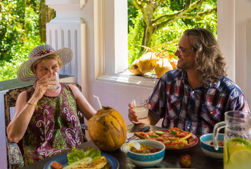 long-haired man and a blonde woman of Caucasian appearance have Breakfast on the veranda of a...