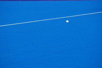Campo de hockey sintético color celeste, con línea divisoria y bocha