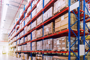 Rows of shelves with goods boxes in huge distribution warehouse at industrial storage factory