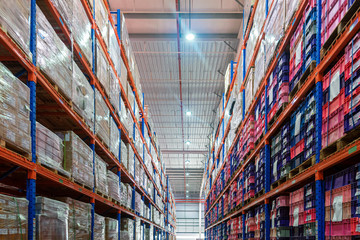 Rows of shelves with goods boxes in huge distribution warehouse at industrial storage factory.