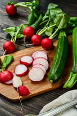 radishes and zucchini sliced on a wooden board. salad with fresh seasonal vegetables. diet food. vegan recipe healthy food
