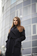 Obraz premium Beautiful girl in a coat in business downtown