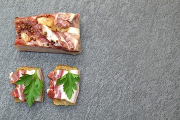 Meat appetizer. Smoked meat with pepper and garlic. Small slices on cereal bread. Dark stone...