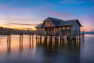 Fototapeta na wymiar Bootshaus mit Steg in Stegen am Ammersee beim Sonnenaufgang
