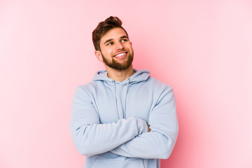 Young caucasian man isolated on pink background smiling confident with crossed arms.