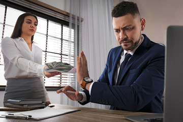Businessman rejecting bribe at table in office